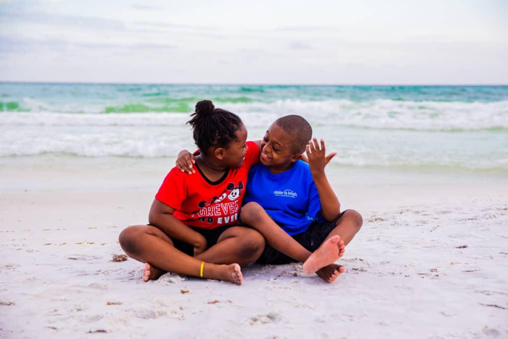 2 Make-A-Wish kids sitting and smiling on a Florida beach